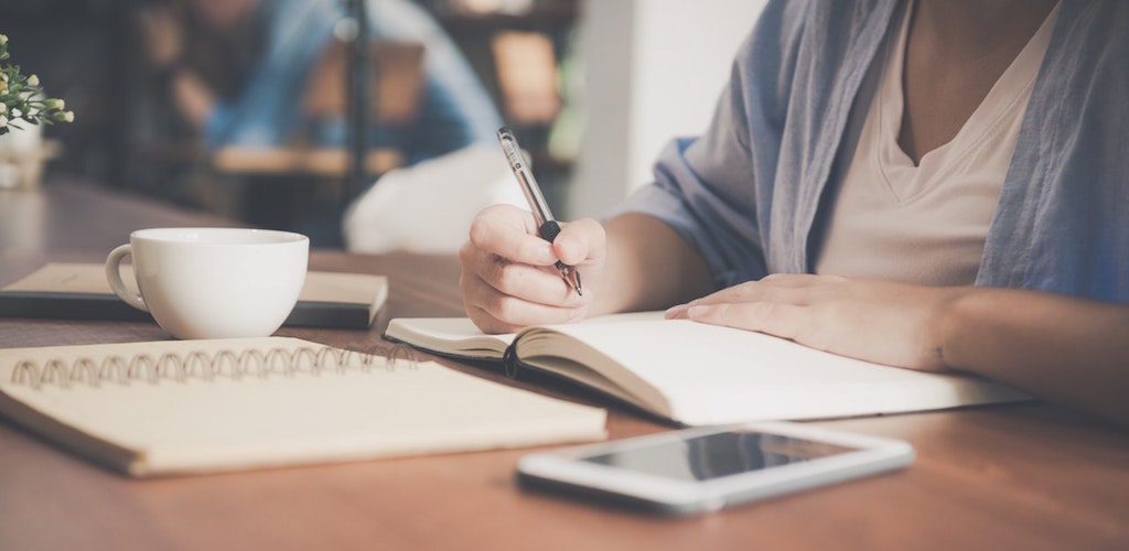 woman sitting in a coffee shop writing